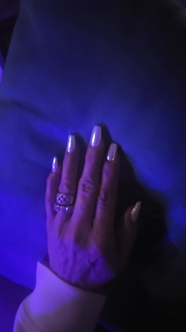 Nail technician painting acrylic nails in a salon chair